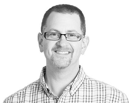 A black and white headshot photograph of a smiling man
