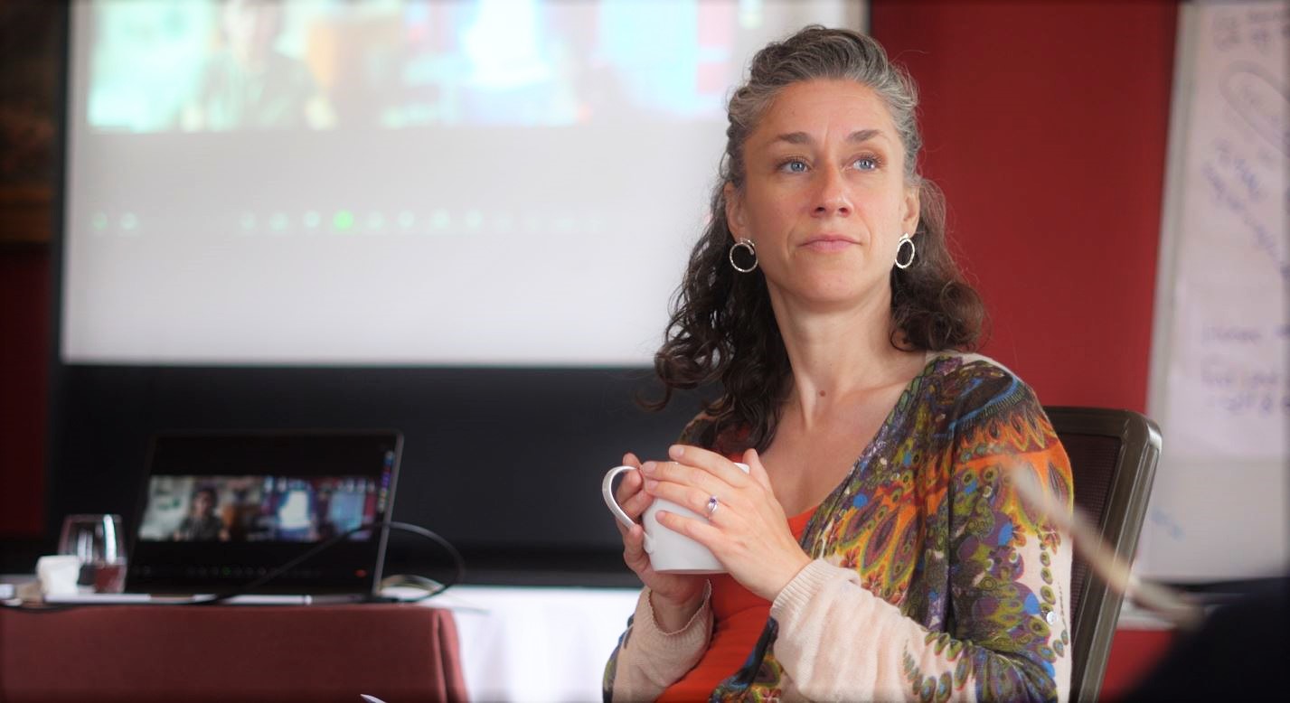 A woman with silver earrings holding a white mug