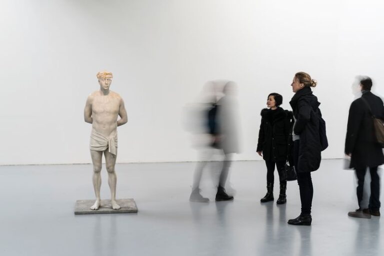 A group of people standing around a white statue