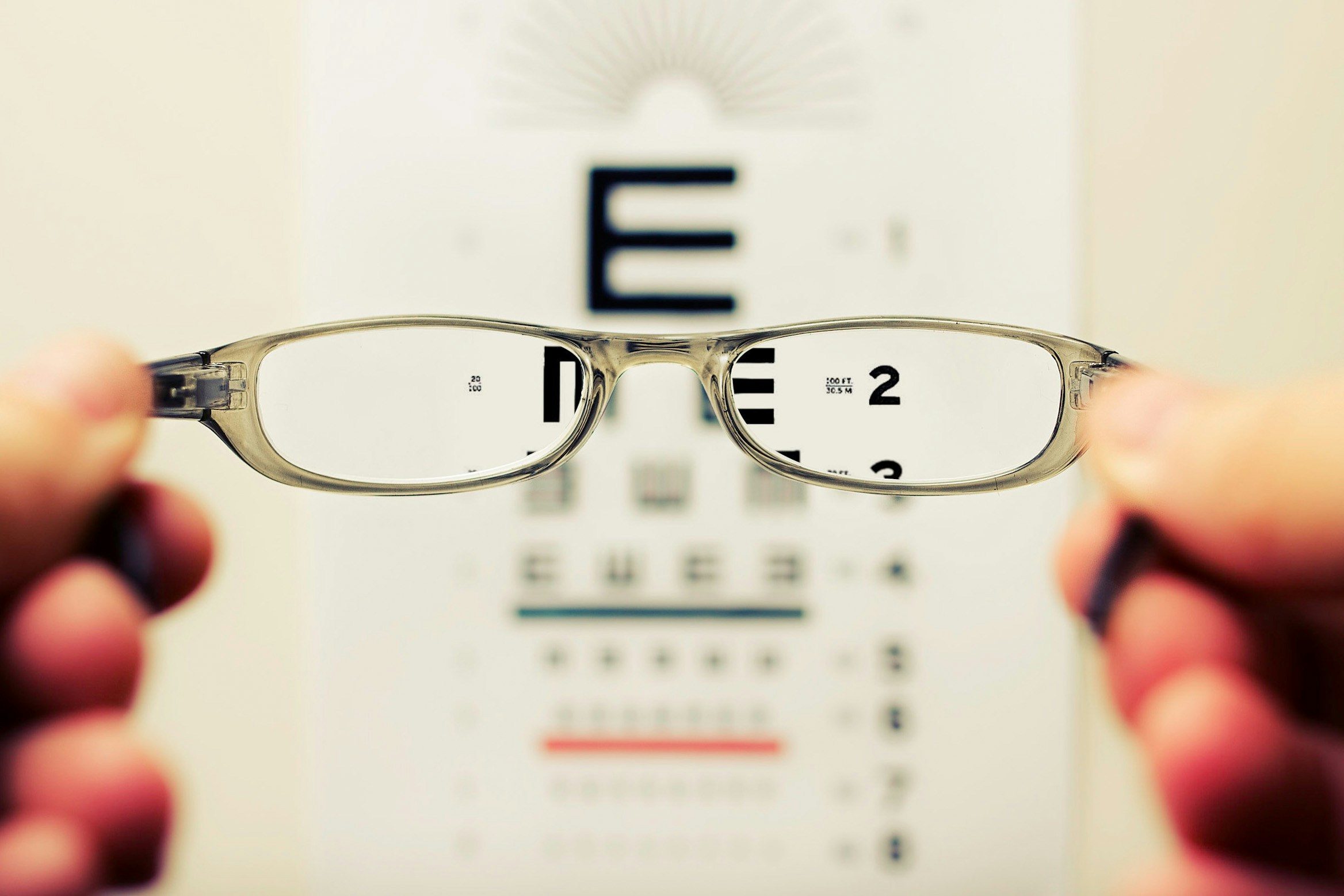 looking through a pair of glasses at a sight test. Letters are in focus through the glasses and blurred outside of the glasses.